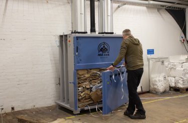 man with cardboard baler